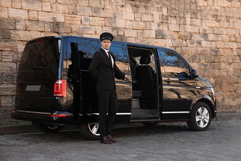 A black van parked in front of a stone wall. 1