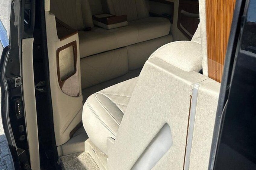 A vehicle interior with beige leather seats, a wooden panel, and a door handle. 4