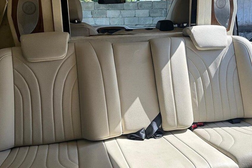 A beige leather car interior with a sunroof, a center console, and a rearview mirror. 3