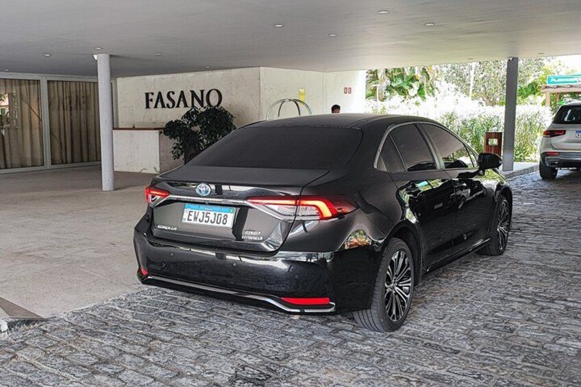 A black Toyota sedan parked in a covered area with a sign reading 'FASANO'. 5