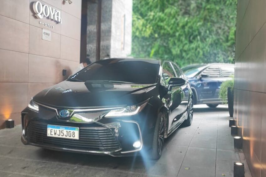 A black Toyota car parked in a covered area with a sign that reads 'QOYA.' 4