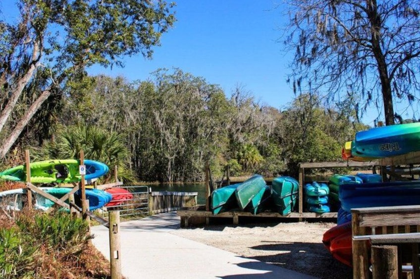 A kayak rental area with canoes and kayaks lined up, surrounded by trees and a clear sky. 2
