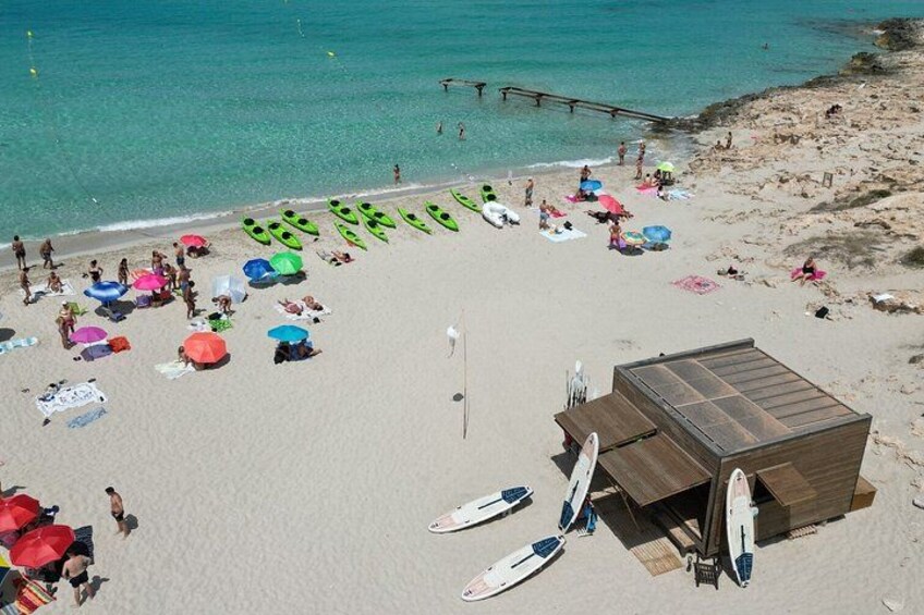 A beach with people sunbathing, colorful umbrellas, and surfboards. 3