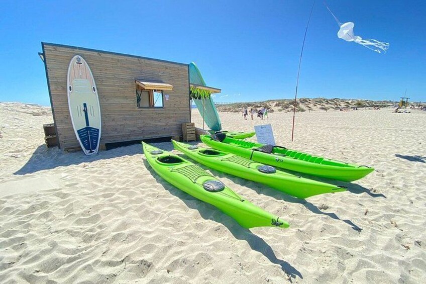 A beach with kayaks, a wooden structure, and a clear sky. 5