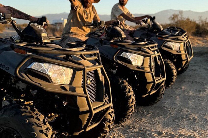 A row of ATVs on a dirt road with a desert landscape in the background. 2