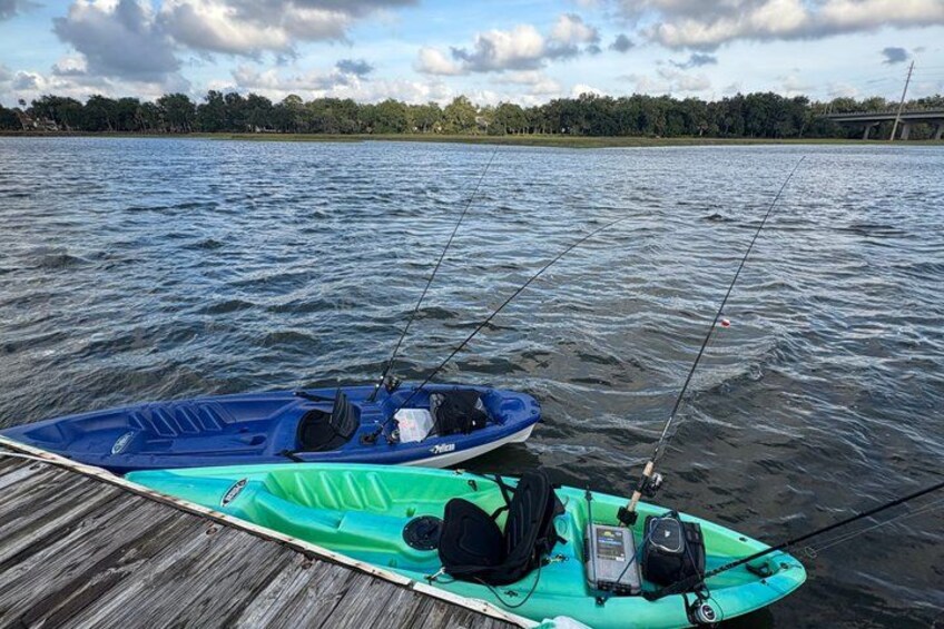 Two kayaks on a wooden dock by a lake with fishing rods. 5