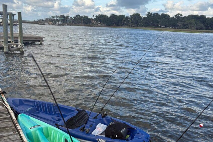 A boat docked at a pier with fishing rods extended into the water. 2