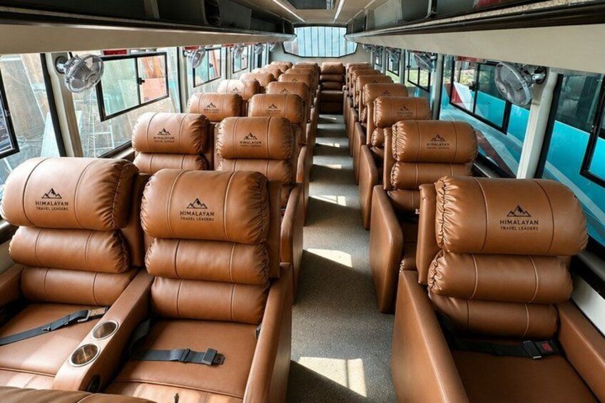 A bus interior with leather seats and a logo on the backrests. 2