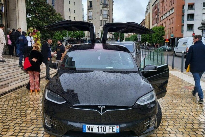 A black car with its doors open, parked on a cobblestone street. 1