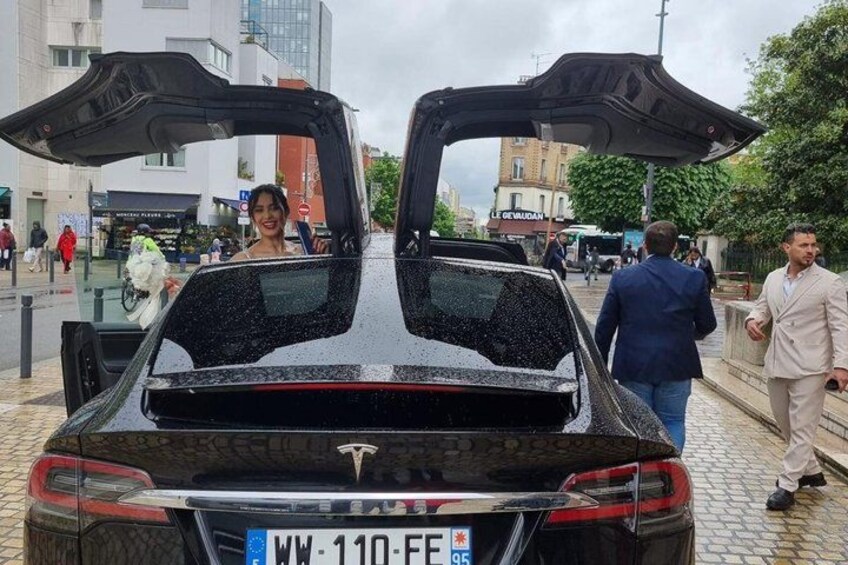 A black luxury car with its trunk open, parked on a cobblestone street. 3