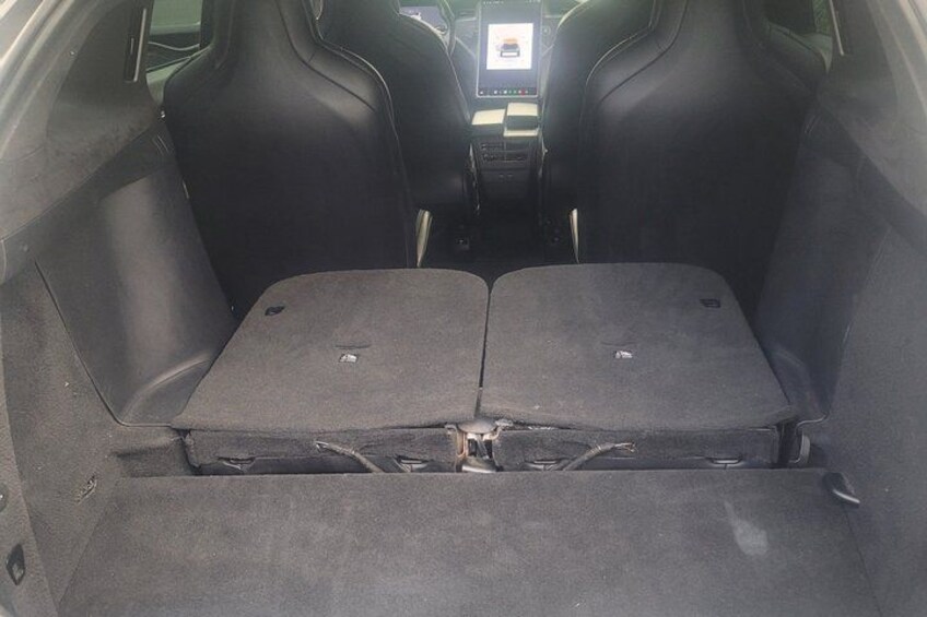 A car's trunk with two seats folded down, a central console, and a rearview mirror. 2