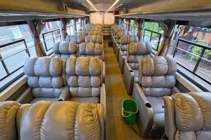 The interior of a train carriage with rows of leather seats and a green bucket on the floor. 2
