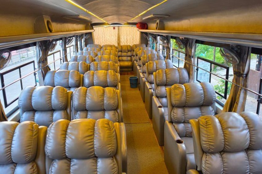 A train interior with rows of leather seats, windows, and overhead luggage compartments. 4
