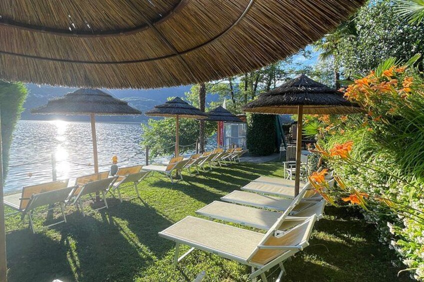 A lakeside lounge area with sun loungers and thatched umbrellas. 5