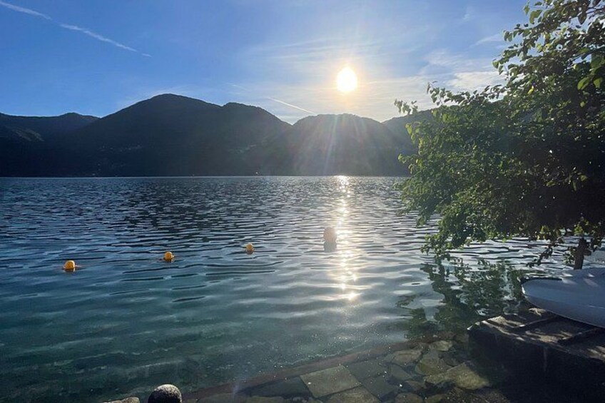 A lake with clear water, a boat docked on the right, and mountains in the background. 2