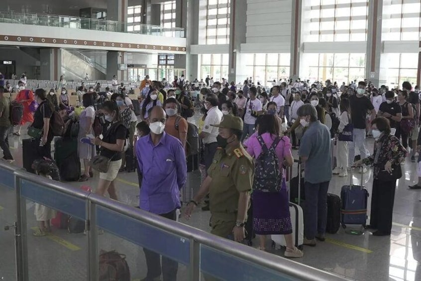 A crowded airport terminal with people standing and walking, some with luggage. 2