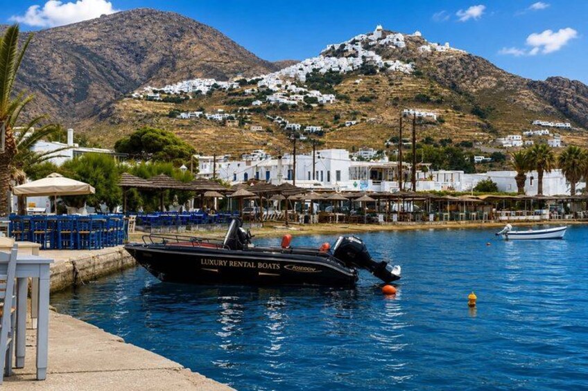 A coastal town with a boat docked at the pier, a mountain in the background, and white buildings. 4