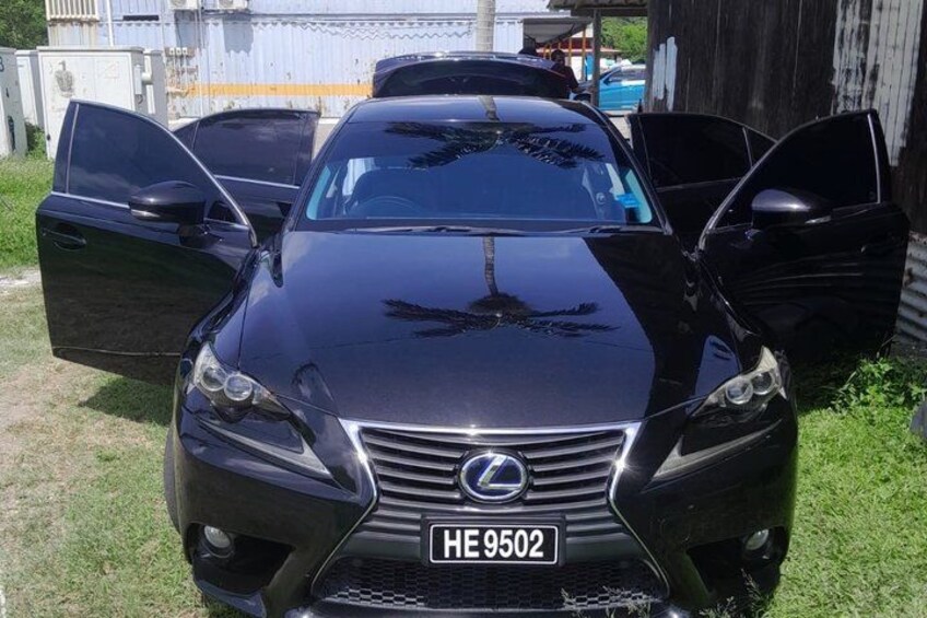 A black Lexus car with its doors open, parked on grass with a building in the background. 1
