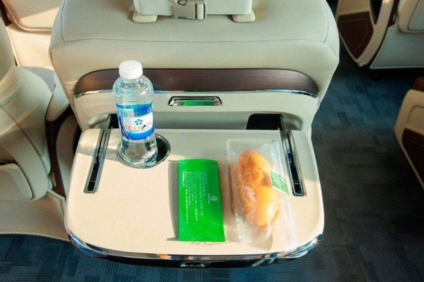 A car seat with a water bottle, a green card, and a plastic-wrapped item. 2