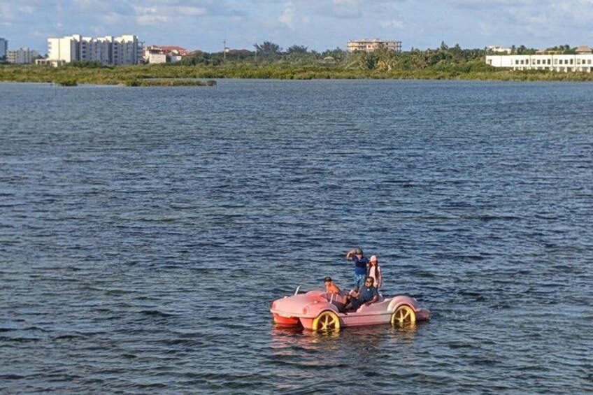 A person on a small boat with a pink and yellow design on a body of water. 2