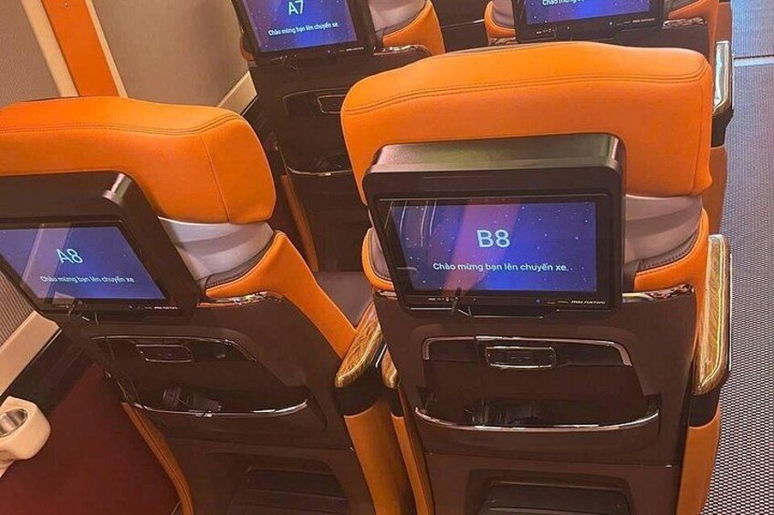 A row of orange seats with individual screens displaying seat numbers A7 and B8. 4