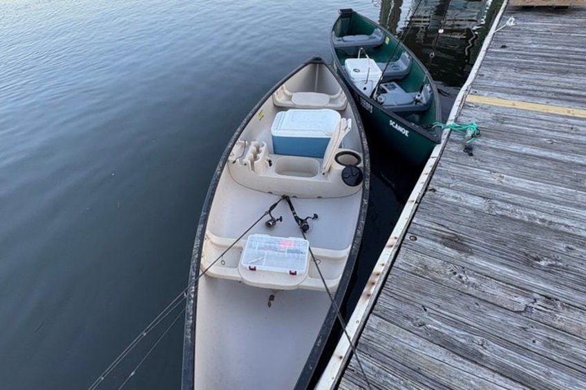 A small boat docked at a wooden pier with a fishing rod and tackle box on deck. 4
