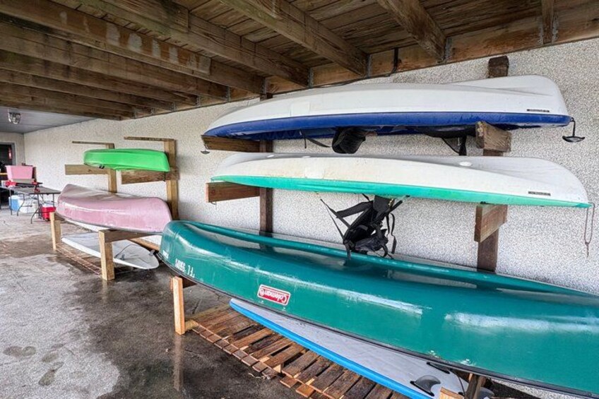 A row of kayaks on wooden racks in a covered area. 1