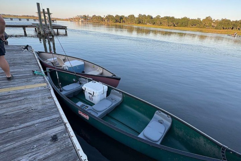 A green boat docked at a wooden pier with a calm lake and trees in the background. 5