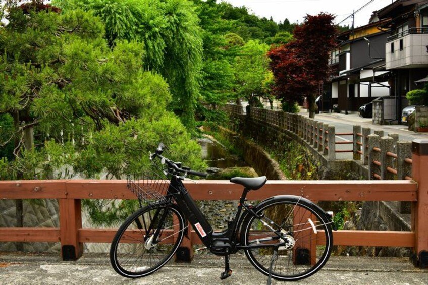 A bicycle parked on a bridge with greenery and buildings in the background. 1