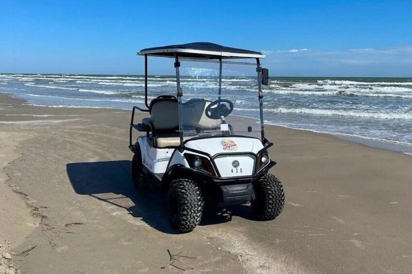 A golf cart on a sandy beach with the ocean in the background. 4