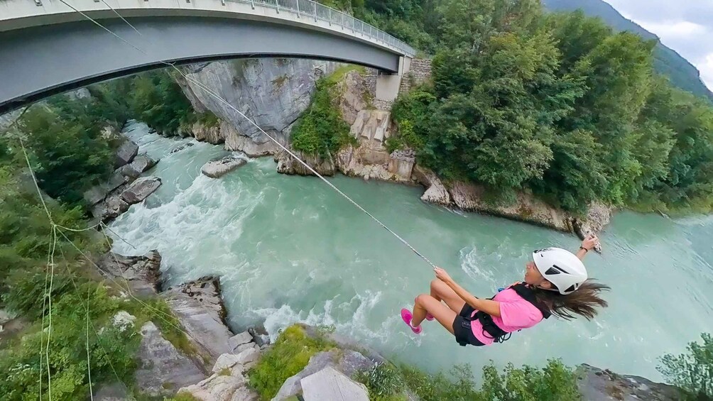 A person bungee jumping from a bridge over a river. 1