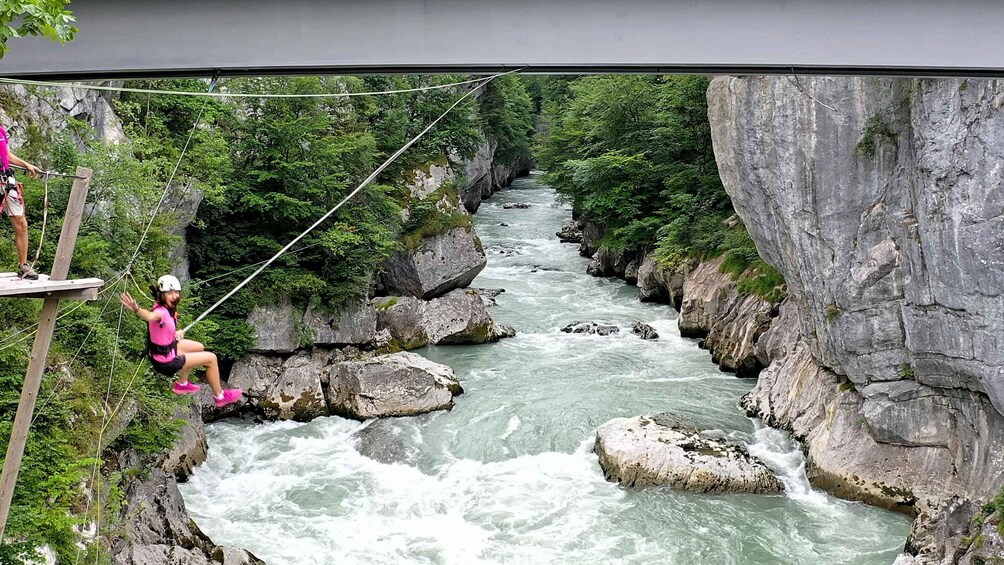 A person rappelling down a river gorge with a bridge overhead. 2