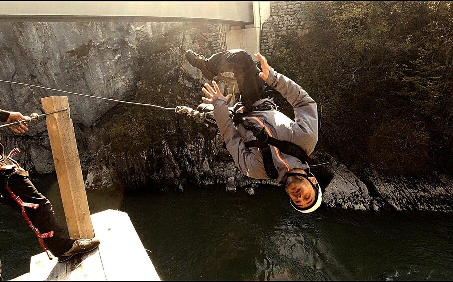 A person bungee jumping from a bridge into a body of water. 3