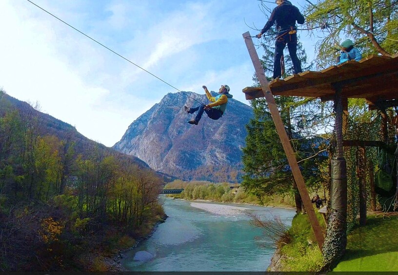 A person bungee jumping over a river with mountains in the background. 4