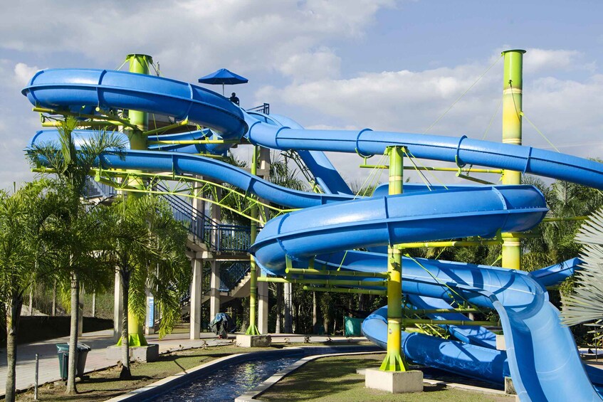 Un parc aquatique doté de plusieurs toboggans aquatiques bleus et d’une piscine. 1