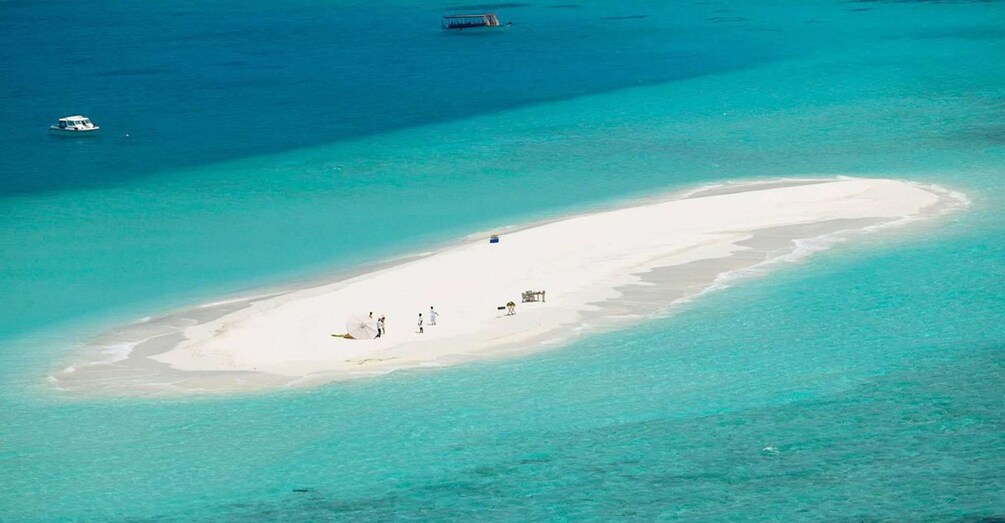A white sandy beach with clear turquoise water, a few people, and a boat in the distance. 5