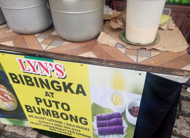 Ein Essensstand mit einem Schild, das Bibingka und Puto Bumbong anbietet. 3