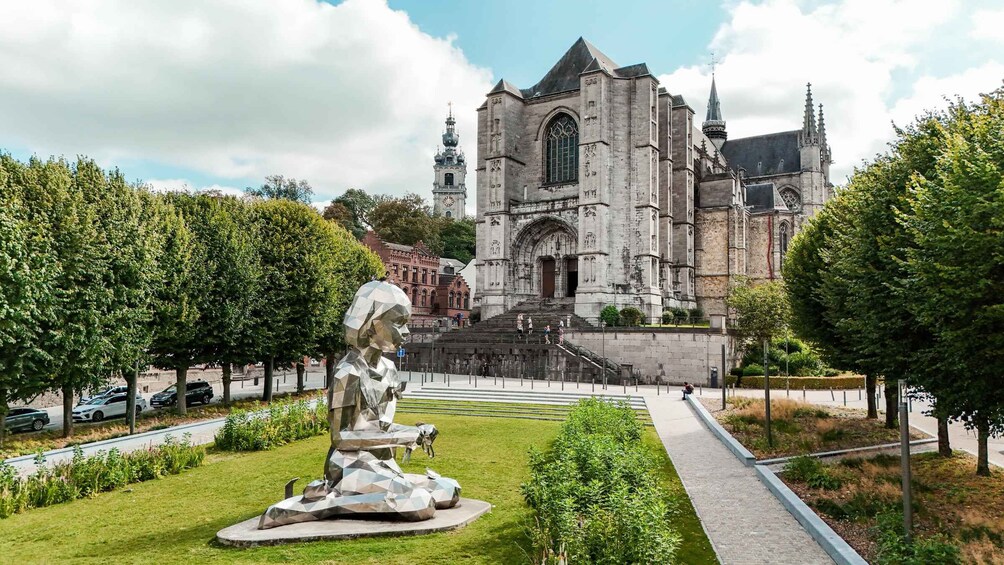 Una iglesia histórica con una alta torre de reloj, rodeada de un jardín bien cuidado con una escultura moderna. 4