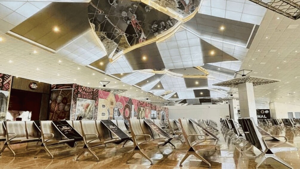 An indoor space with a high ceiling, geometric ceiling design, and rows of chairs. 2