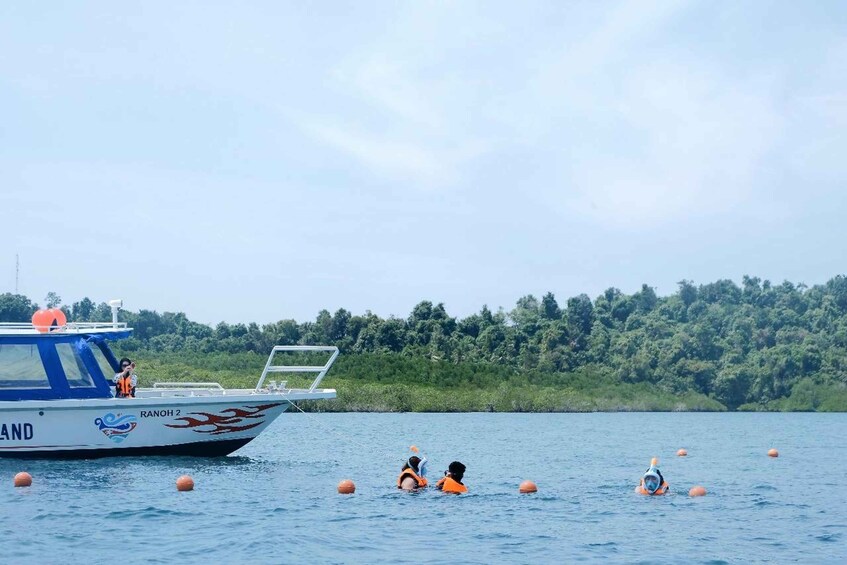 Un bateau nommé « RANOH 2 » sur un lac, avec des personnes qui nagent et flottent sur des bouées. 3