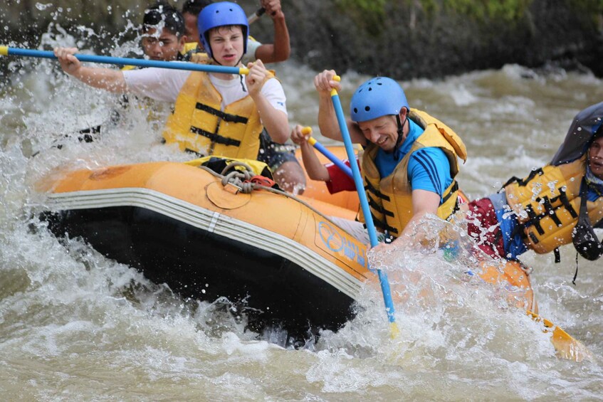 A group of people in a raft navigating through a river with rapids. 4