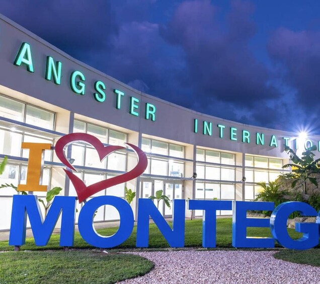 Un bâtiment portant l’enseigne « ANGSTER INTERNATIONAL » et sur lequel on peut voir, devant l’entrée, une grande affiche avec le message « J’aime MONTEG ». 2