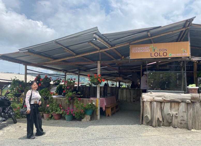 Un mercado al aire libre rústico con una estructura cubierta, plantas en macetas y un letrero que anuncia un restaurante. 4