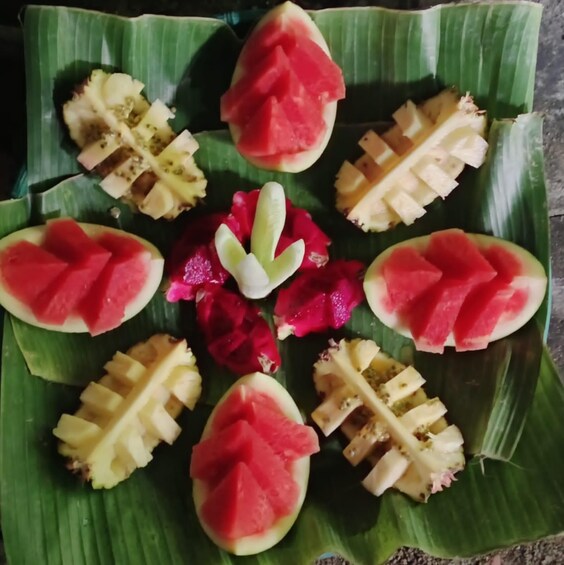 Un plato de comida con sandía, pitahaya y piña dispuestos sobre una hoja de plátano. 5