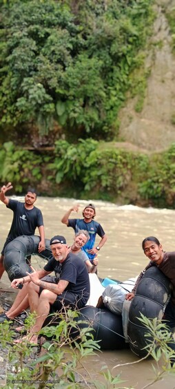 Un grupo de personas sentadas en una balsa inflable cerca de un río rodeado de vegetación. 1