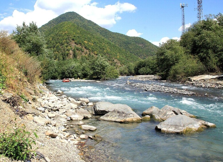 Une rivière avec des rochers, une montagne et un radeau rouge. 2