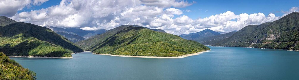 Un paysage côtier avec une petite île entourée d’eaux bleues et calmes et de collines verdoyantes. 3