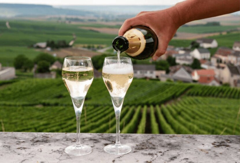 Iemand schenkt champagne in twee glazen. 2