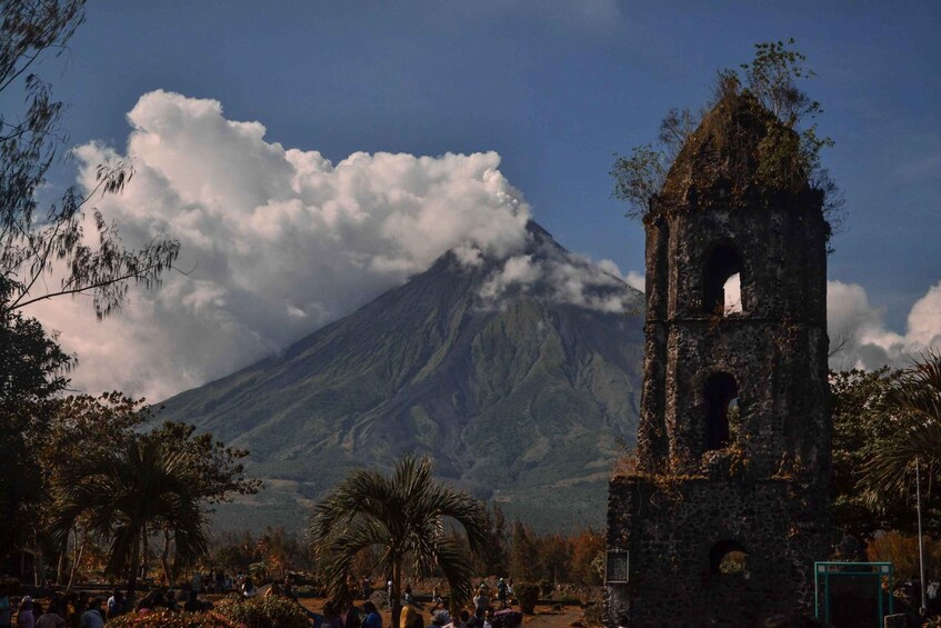 Un volcán, una iglesia y gente en un parque. 3