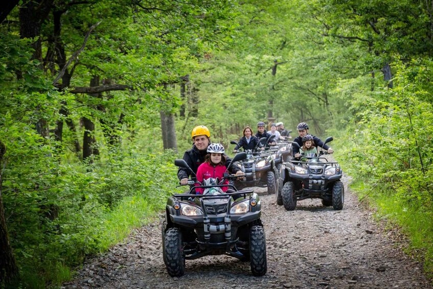 Un groupe de personnes circule à bord de quads sur un chemin de terre, entouré d’une végétation luxuriante. 2